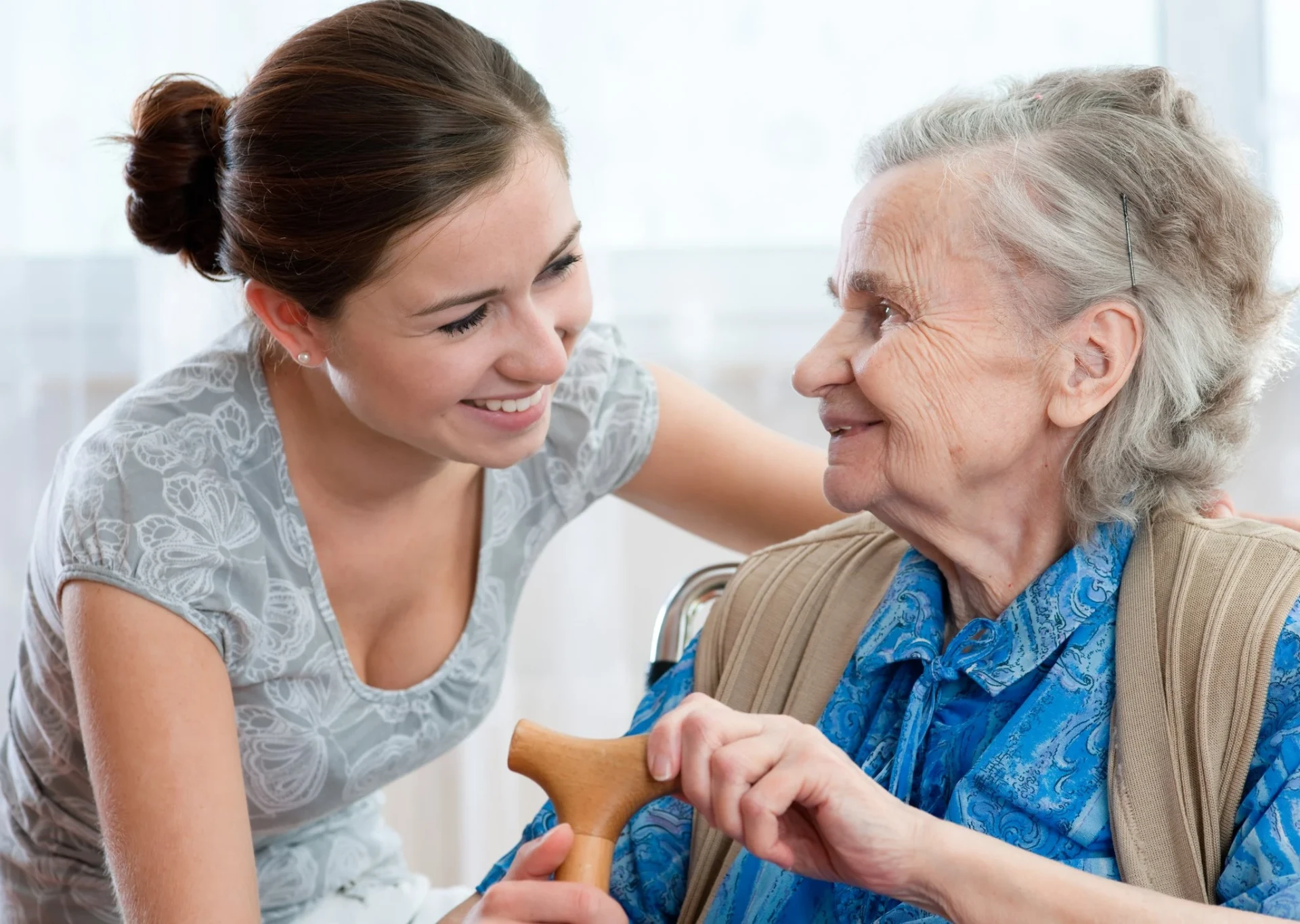 Caregiver hugging a smiling elderly man at home