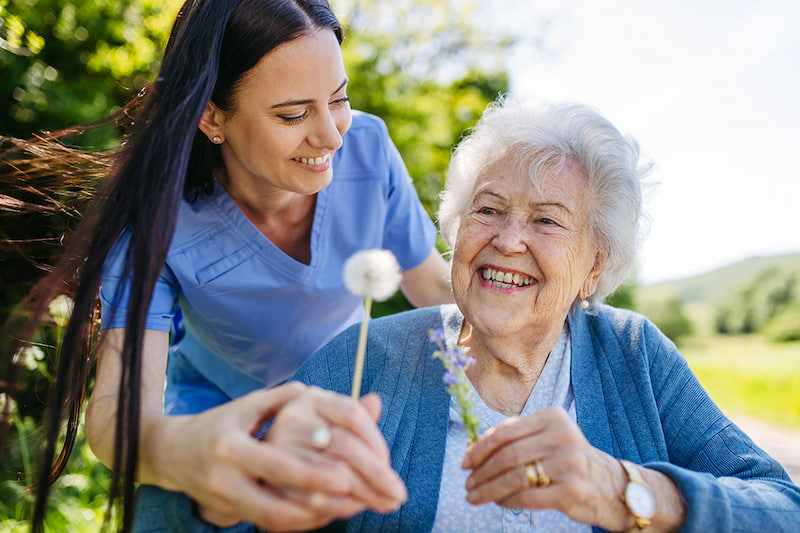 Caregiver and elderly client laughing together on a couch