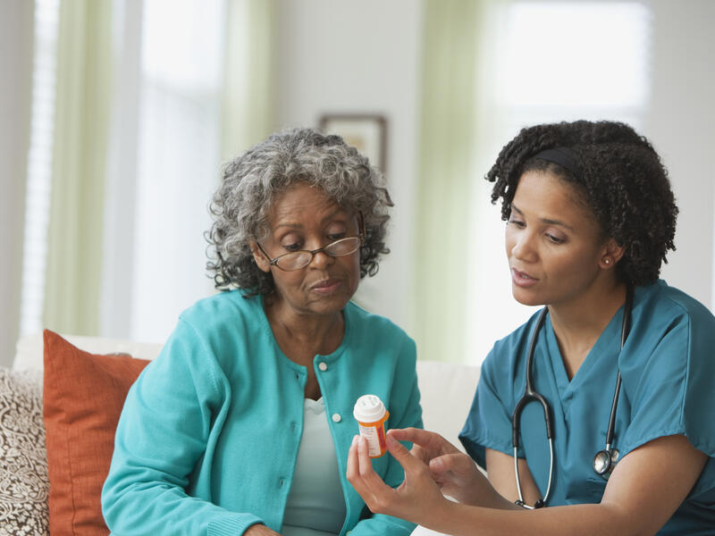 Caregiver helping an elderly man organize his medications