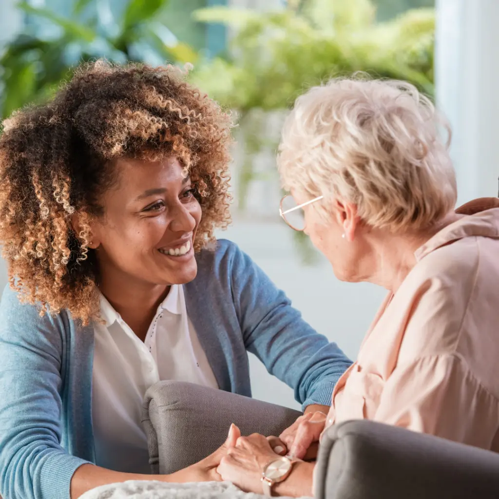 Caregiver warmly assisting an elderly woman at home